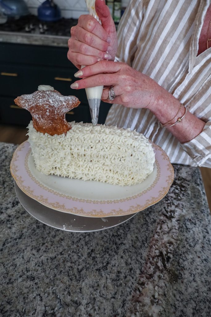 decorating the gluten free lamb cake with buttercream frosting