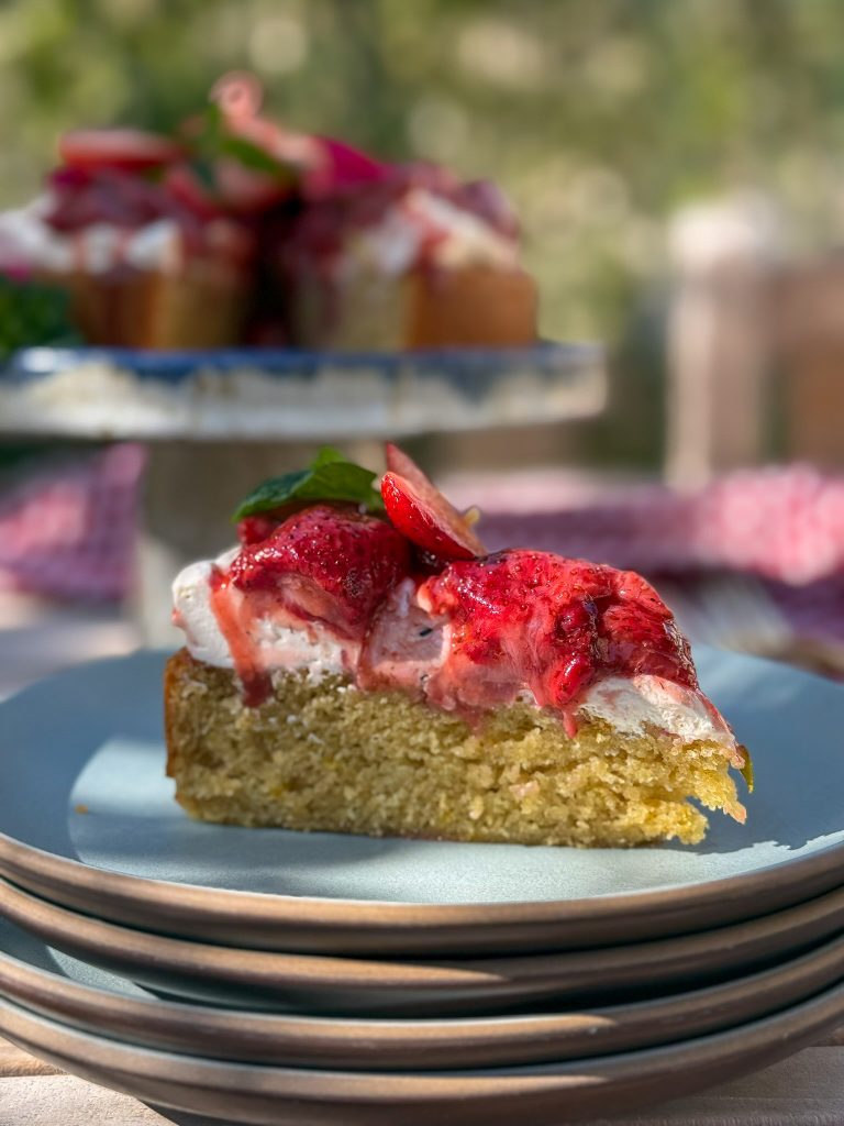 Slice of gluten free buttermilk cake on a stack of blue heath plates