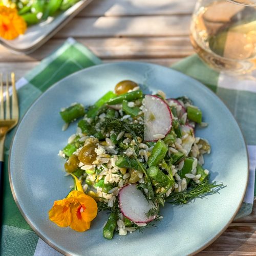 Spring orzo salad with smashed olive dressing on a blue plate