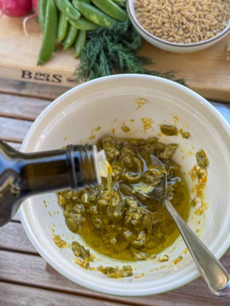 adding olive oil to smashed olive dressing
